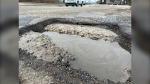 A pothole filled with muddy water on Abinojii Mikanah, formerly Bishop Grandin Boulevard, is pictured on April 15, 2024. (Scott Andersson/CTV News Winnipeg)