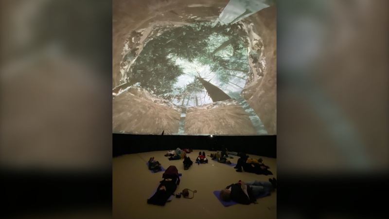 Audience members lay on the ground to watch 'The Brain' -- a 360-degree video projection mapped on to a large dome. (Image courtesy of Kelly Proudfoot)