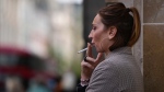 A woman smokes on a street, in London, Tuesday, April 16, 2024. (AP Photo/Kin Cheung)