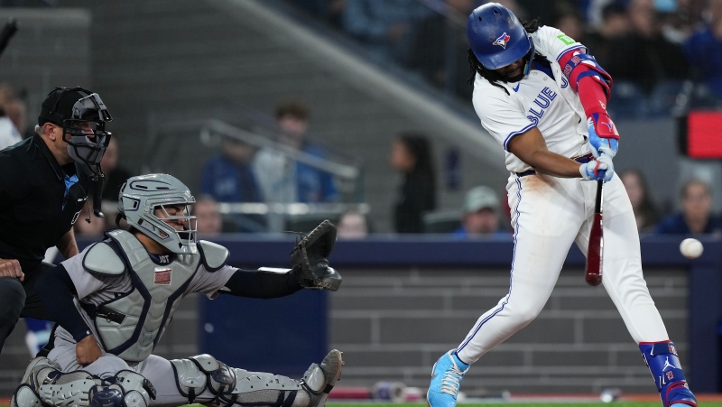 Toronto Blue Jays' Vladimir Guerrero Jr. (27) hits an RBI single as New York Yankees catcher Jose Trevino (39) looks on during fourth inning American League MLB baseball action in Toronto on Tuesday, April 16, 2024. THE CANADIAN PRESS/Nathan Denette