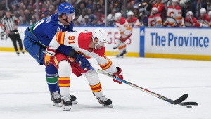 Vancouver Canucks' Nikita Zadorov, back left, checks Calgary Flames' Nazem Kadri during the first period of an NHL hockey game in Vancouver, on Tuesday, April 16, 2024. THE CANADIAN PRESS/Darryl Dyck