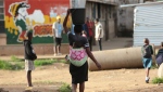 A woman carries her baby and a bucket of water in Harare on April 6, 2020. (AP Photo/Tsvangirayi Mukwazhi)