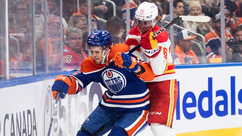 Edmonton Oilers defenceman Philip Broberg and Calgary Flames forward Martin Pospisil battle for the puck during NHL preseason action on Oct. 4, 2023.(Jason Franson/The Canadian Press)