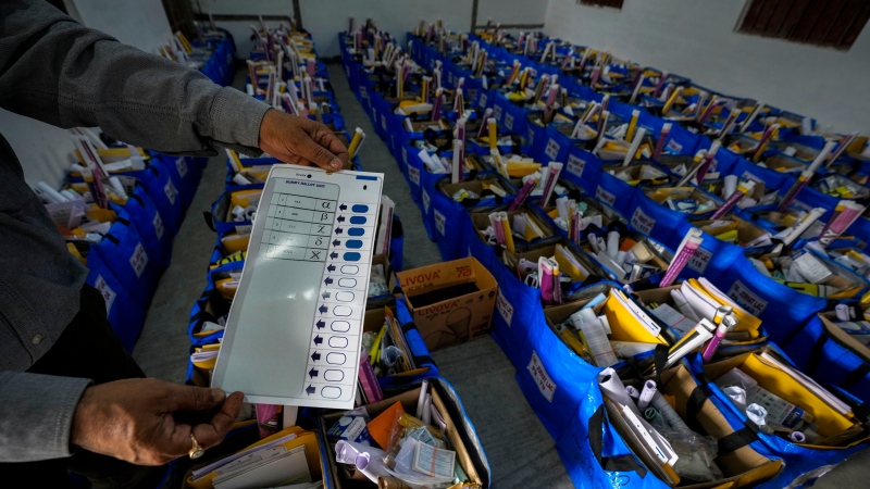 An official holds a mock ballot paper as he prepares bags of election material to be distributed along with the Electronic Voting Machines (EVMs) ahead of the national parliamentary elections in Jorhat, India, Wednesday, April 17, 2024. (THE CANADIAN PRESS/AP/Anupam Nath)
