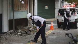 Police officers clean the debris from an earthquake in Uwajima, Ehime prefecture, western Japan Thursday, April 18, 2024. (Kyodo News via AP)