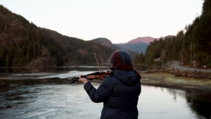 Carol Love plays Tennessee Whiskey on her violin in an effort to try and lure a two-year-old orca calf out of a lagoon she's been living in for over three weeks at Zeballos, B.C., on Wednesday, April 17, 2024. THE CANADIAN PRESS/Chad Hipolito