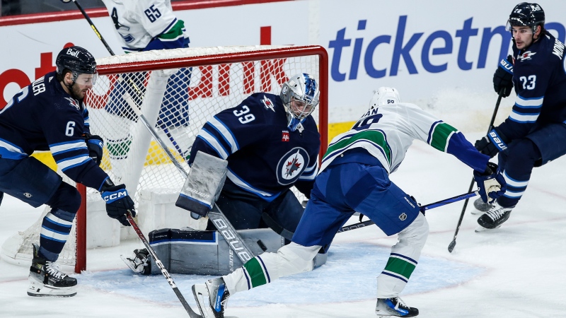 Winnipeg Jets goaltender Laurent Brossoit (39) saves the shot from Vancouver Canucks' Nils Aman (88) as Colin Miller (6) and Sean Monahan (23) defend during second period NHL action in Winnipeg on Thursday, April 18, 2024. THE CANADIAN PRESS/John Woods