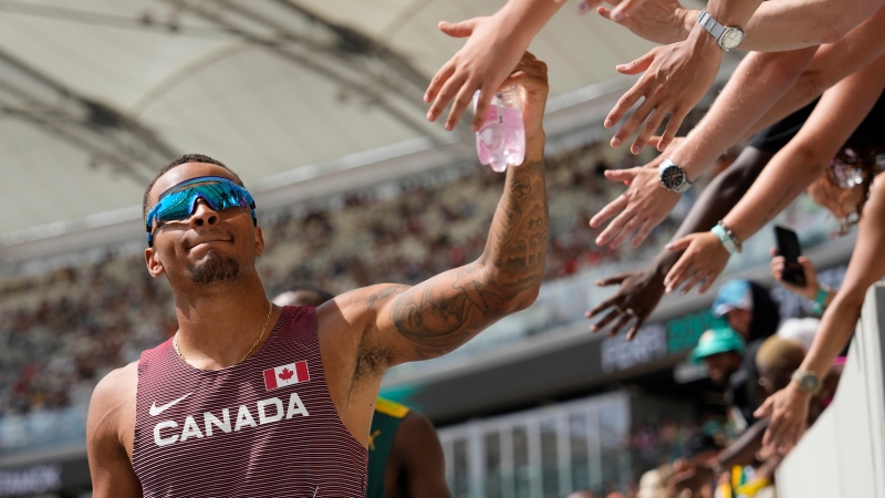 Andre De Grasse receives high fives from fans during the men's 200-metre heat at the World Athletics Championships in Budapest, Hungary, Wednesday, Aug. 23, 2023. (AP/Ashley Landis)