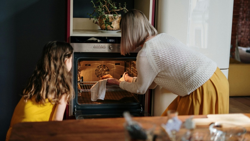 A woman and child put food in the oven in this undated file image. (Cottonbro studio / Pexels)