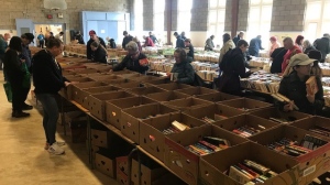 People look through boxes of books at the CFUW K-W annual Used Book Sale on April 19, 2024. (Dave Pettitt/CTV News)