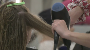 A hair stylist works on a client's hair as part of a 'Blow-a-thon' fundraiser in Cambridge on April 21, 2024. (Shelby Knox/CTV News)