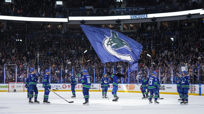 Vancouver Canucks players gather at centre ice to raise their sticks to the fans after defeating the Calgary Flames during their final NHL regular season home hockey game, in Vancouver, on Tuesday, April 16, 2024. THE CANADIAN PRESS/Darryl Dyck