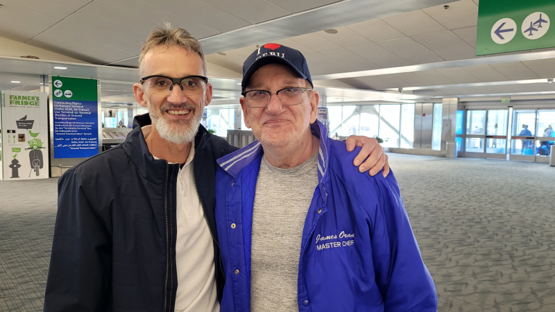 Michael Anderberg, 57, and Jim Oran, 81, take their first photo together at Detroit Metropolitan Airport on April 18, 2024. (Sanjay Maru/CTV News Windsor)