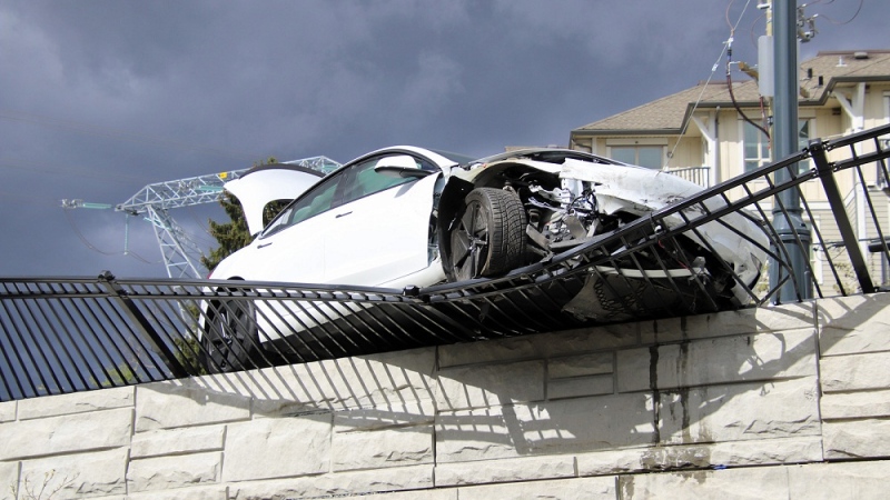 A tesla hangs over a wall in Surrey after a crash on Sunday, April 21. 