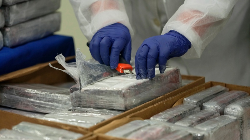 A member of the Portuguese police opens a packet of cocaine being displayed for the media at the police headquarters in Lisbon, Tuesday, May 2, 2023. (AP Photo/Armando Franca) 