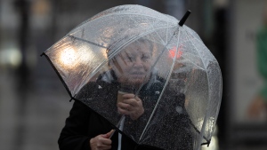 A pedestrian shields themselves from rain and wind in Halifax on Thursday, January 26, 2023. THE CANADIAN PRESS/Darren Calabrese