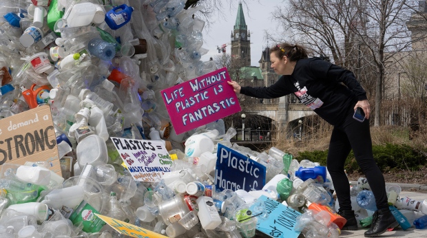 Activist Dianne Peterson places a sign on a public art installation outside a United Nations conference on plastics, Tuesday, April 23, 2024 in Ottawa. (Adrian Wyld/THE CANADIAN PRESS)