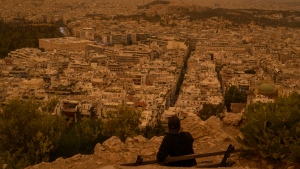 A Tourists seats on a bench at the Lycabettus hill as the city of Athens with the ancient Acropolis hill is seen at the background, on Tuesday, April 23, 2024. (Petros Giannakouris / AP Photo)