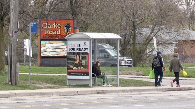 A bus passenger waits at the London Transit stop in front of Clarke Road Secondary School on April 23, 2024.  (Daryl Newcombe/CTV News London)