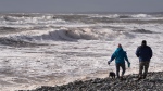 Hikers walk along Lawrencetown Beach Provincial Park in Lawrencetown, N.S., as waves and heavy winds batter the coastline on Sunday, January 14, 2024. THE CANADIAN PRESS/Darren Calabrese