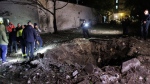 People looks on a crater after a Russian attack on residential neighbourhood in Kharkiv, Ukraine, on Wednesday, April 24, 2024. (AP Photo/Yakiv Liashenko)