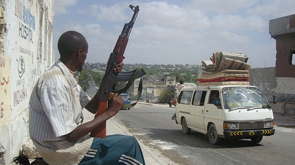 A Somali government soldier in plain clothes guards a road block as residents load their belongings on a minibus as they flee their neighborhood in the capital, Mogadishu, Somalia, where intense fighting broke out for the third day between Somali government forces backed the AU forces and Islamist insurgents on Friday March 12, 2010. (AP /  Farh Abdi Warsameh)s