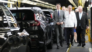 Prime Minister Justin Trudeau, Honda executive Toshihiro Mibe and Ontario Premier Doug Ford walk along an assembly line at an event announcing plans for a Honda electric vehicle battery plant in Alliston, Ont. (Nathan Denette/Canadian Press)
