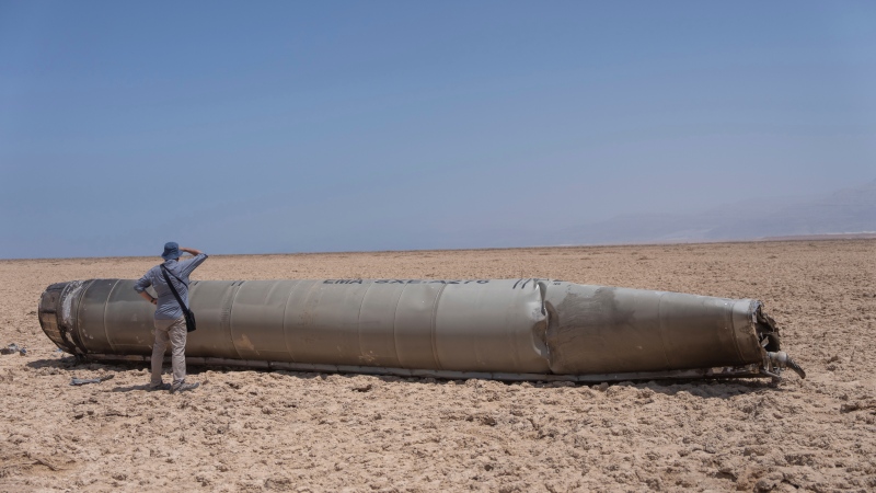 A photojournalist looks at part of the intercepted ballistic missile that fell near the Dead Sea in Israel, Sunday, April 21, 2024. (AP Photo/ Ohad Zwigenberg) 