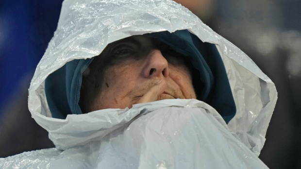 A fan watches in the rain during the fourth inning of a baseball game between the Kansas City Royals and the Toronto Blue Jays Thursday, April 25, 2024, in Kansas City, Mo. (AP Photo/Charlie Riedel)