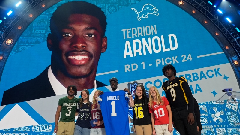 Alabama cornerback Terrion Arnold, center, poses after being chosen by the Detroit Lions with the 24th overall pick during the first round of the NFL football draft, Thursday, April 25, 2024, in Detroit. (AP Photo/Paul Sancya)