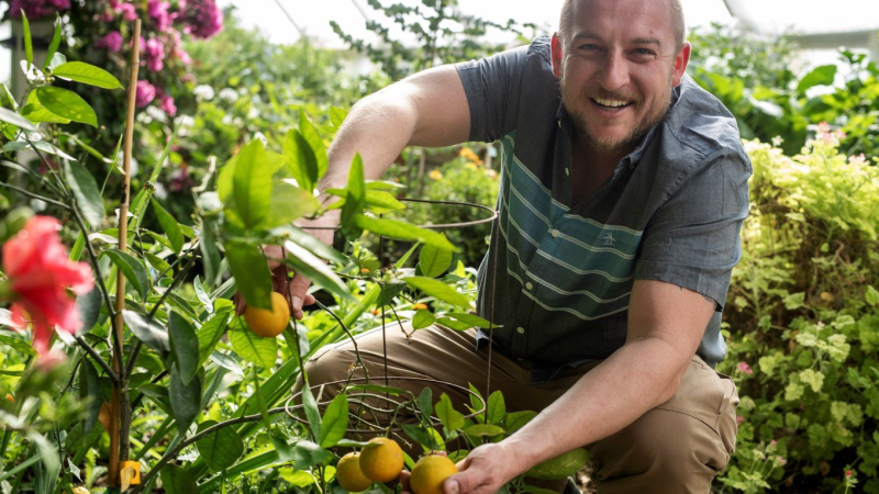 Dean Sopher poses for a portrait with one of his orange trees in his greenhouse outside Saskatoon on Friday, April 5, 2024. THE CANADIAN PRESS/Liam Richards