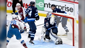 Winnipeg Jets' goaltender Connor Hellebuyck (37), Neal Pionk (4) and Dylan Samberg (54) keep their eyes on a bouncing puck while under pressure from Colorado Avalanche's Ross Colton (20) and Miles Wood (28) during the third period in Game 2 of their NHL hockey Stanley Cup first-round playoff series in Winnipeg, Tuesday April 23, 2024. THE CANADIAN PRESS/Fred Greenslade