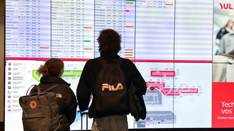 Travellers look at a departure information board at Pierre Elliott Trudeau International Airport in Montreal, Friday, Dec. 23, 2023. (Christinne Muschi / The Canadian Press)