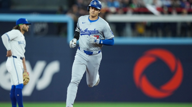 Los Angeles Dodgers designated hitter Shohei Ohtani (17) rounds the bases past Toronto Blue Jays shortstop Bo Bichette (11) after hitting a solo home run during first inning Interleague MLB baseball action in Toronto on Friday, April 26, 2024. THE CANADIAN PRESS/Nathan Denette