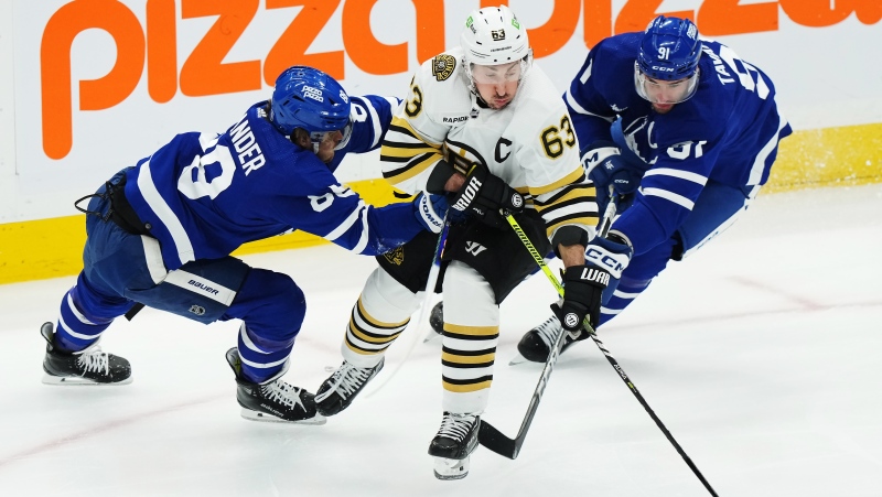 Boston Bruins' Brad Marchand (63) is checked by Toronto Maple Leafs' William Nylander (88) and John Tavares (91) during first period action in Game 4 of an NHL hockey Stanley Cup first-round playoff series in Toronto on Saturday, April 27, 2024. THE CANADIAN PRESS/Nathan Denette