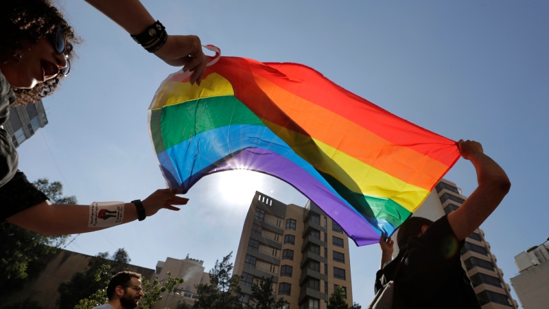 FILE - Activists from the Lesbian, Gay, Bisexual, and Transgender (LGBTQ) community in Lebanon shout slogans and hold up a rainbow demanding rights during a protest in Beirut, Lebanon, June 27, 2020. (AP Photo/Hassan Ammar, File)