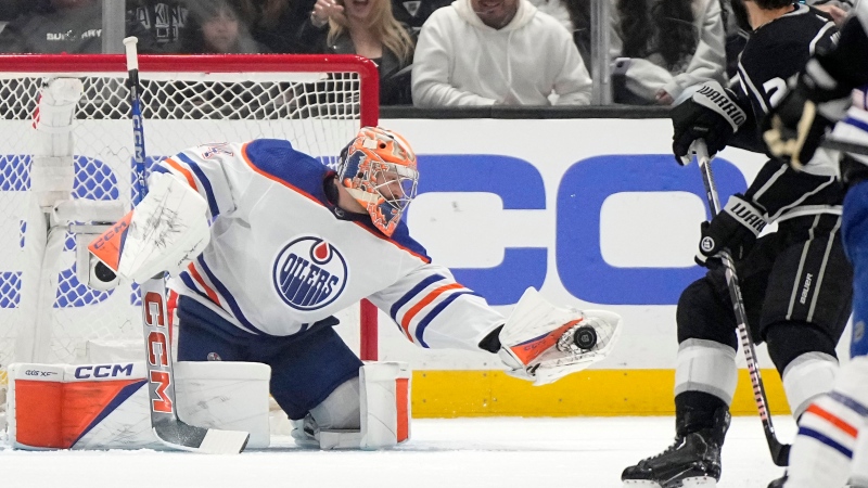 Edmonton Oilers goaltender Stuart Skinner, left, makes a glove save as Los Angeles Kings center Phillip Danault watches during the first period in Game 4 of an NHL hockey Stanley Cup first-round playoff series Sunday, April 28, 2024, in Los Angeles. (Mark J. Terrill / The Associated Press)