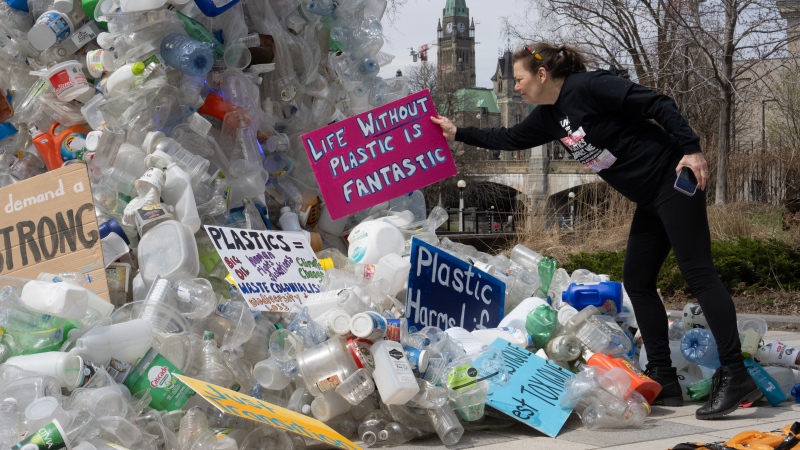 Activist Dianne Peterson places a sign on a public art installation outside a United Nations conference on plastics, Tuesday, April 23, 2024 in Ottawa. (Adrian Wyld, The Canadian Press)