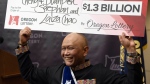 Cheng "Charlie" Saephan holds a check above his head after speaking during a news conference where it was revealed that he was one of the winners of the $1.3 billion Powerball jackpot at the Oregon Lottery headquarters on Monday, April 29, 2024, in Salem, Ore. (AP Photo/Jenny Kane)