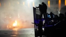 A police car on fire as riot police prepare to stop protesters in the centre of Almaty, Kazakhstan, Wednesday, Jan. 5, 2022. (AP Photo/Vladimir Tretyakov)