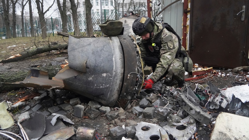 A Ukrainian police officer inspects a rocket part near a residential building damaged by a Russian missile strike in Kharkiv, Ukraine, Tuesday, Jan. 2, 2024. (AP Photo/Andrii Marienko)