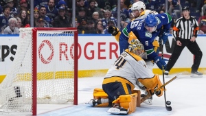 Vancouver Canucks' Brock Boeser (6) is stopped by Nashville Predators goalie Juuse Saros as he's checked by Alexandre Carrier, back, during the third period in Game 5 of an NHL hockey Stanley Cup first-round playoff series, in Vancouver, on Tuesday, April 30, 2024. THE CANADIAN PRESS/Darryl Dyck