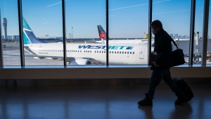 Passengers walk past Air Canada and WestJet planes at Calgary International Airport in Calgary, Alta., Wednesday, Aug. 31, 2022. THE CANADIAN PRESS/Jeff McIntosh