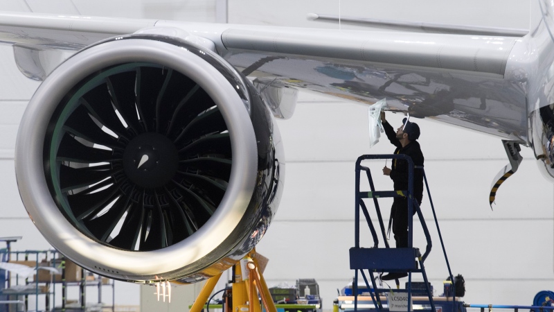 An Airbus employee works under the wing of an Airbus A220 at the assembly plant in Mirabel, Que., Thursday, February 20, 2020. THE CANADIAN PRESS/Graham Hughes