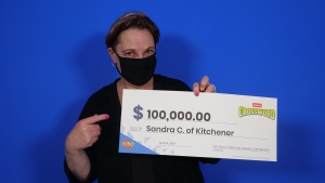 Sandra Companion holds a large novelty cheque after winning $100,000 in OLG's Instant Crossword Tripler. (Submitted: OLG)
