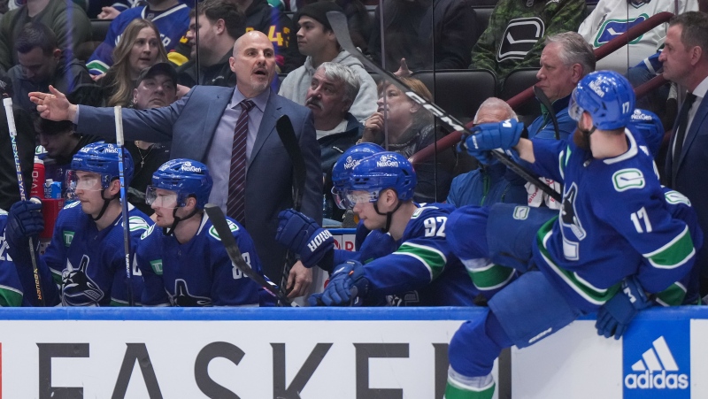 Canucks head coach Rick Tocchet, back left, gives instructions to Filip Hronek, front right, during a game against the Montreal Canadiens in Vancouver on March 21, 2024. (THE CANADIAN PRESS/Darryl Dyck)
