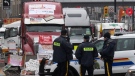 Police officers keep an eye on protest trucks, in Ottawa, Thursday, Feb. 17, 2022. THE CANADIAN PRESS/Adrian Wyld