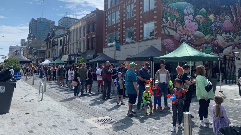 Long lineup of people waiting to get their free comic books on Dundas Street in London, Ont. on May 4, 2024.  (Reta Ismail/CTV News London)