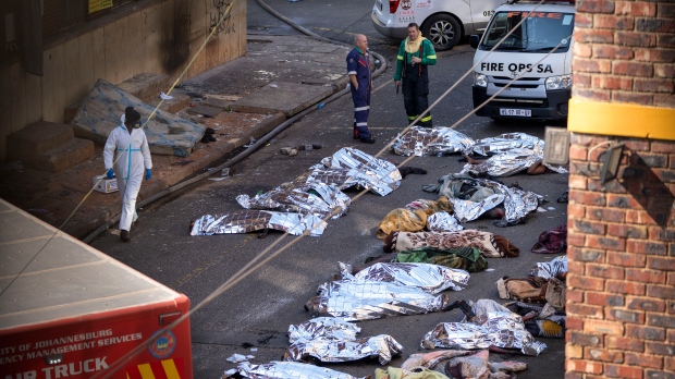 Medics stand by the covered bodies of victims of a deadly blaze in Johannesburg, Thursday, Aug. 31, 2023. (AP Photo/Jerome Delay/File)