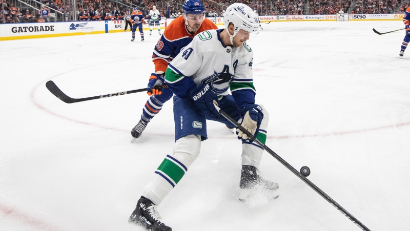Vancouver Canucks' Elias Pettersson (40) and Edmonton Oilers' Sam Carrick (39) battle for the puck during third period NHL action in Edmonton, Saturday, April 13, 2024. THE CANADIAN PRESS/Jason Franson